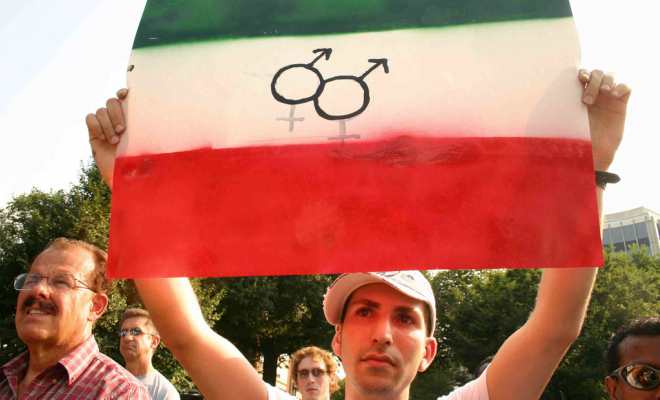 A photo of a man holding up an Iranian flag and equal rights logos.