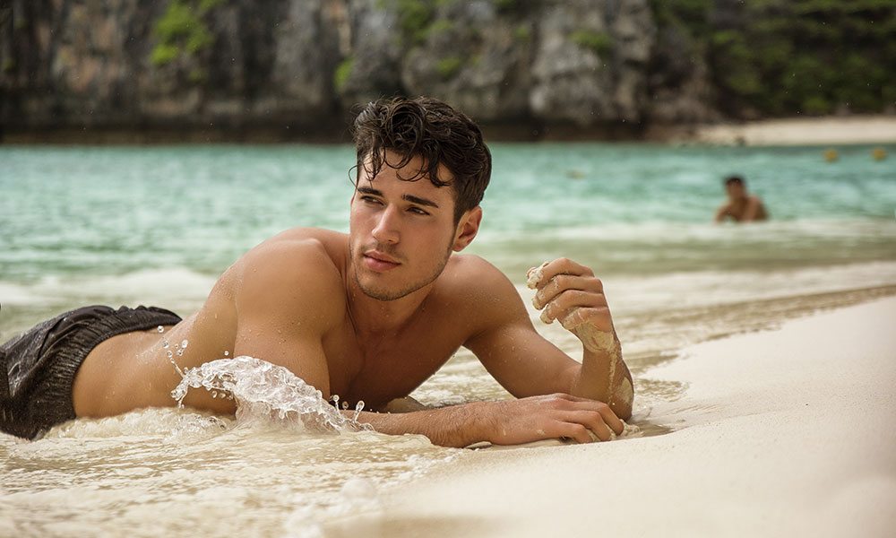 Man laying on a beach in the sand