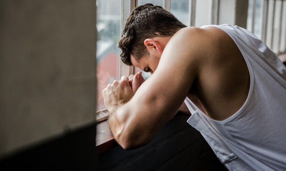 Muscular man leaning on window