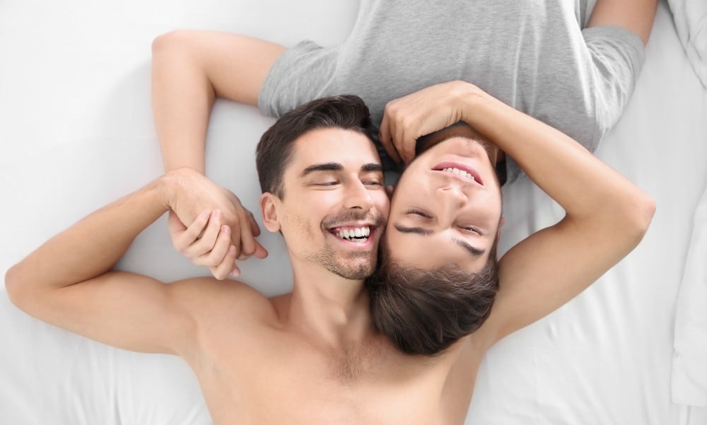 A young gay couple laying on a bed