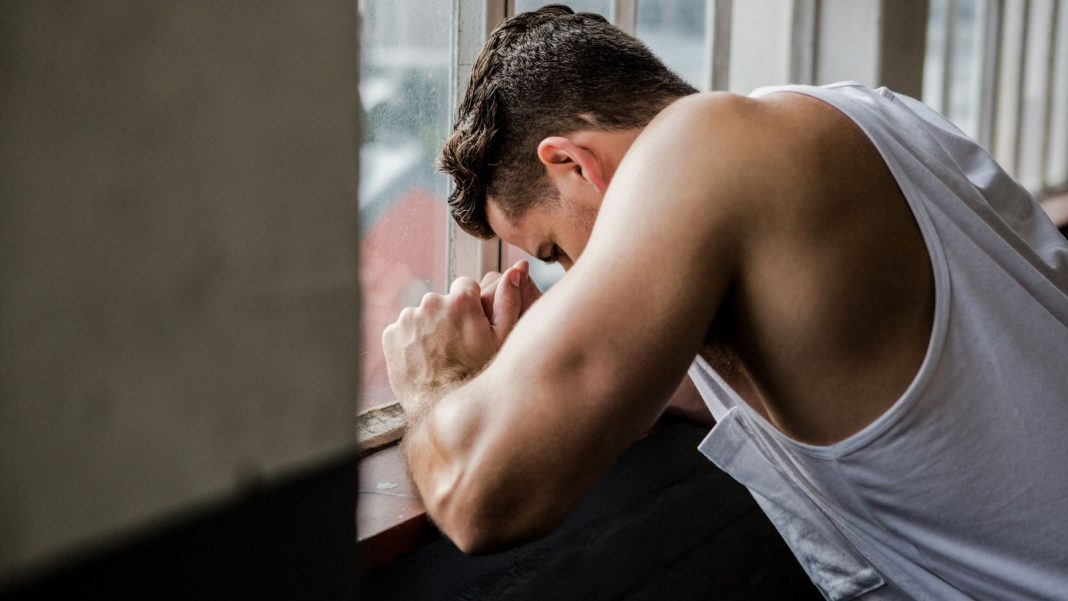 Muscular man leaning on window