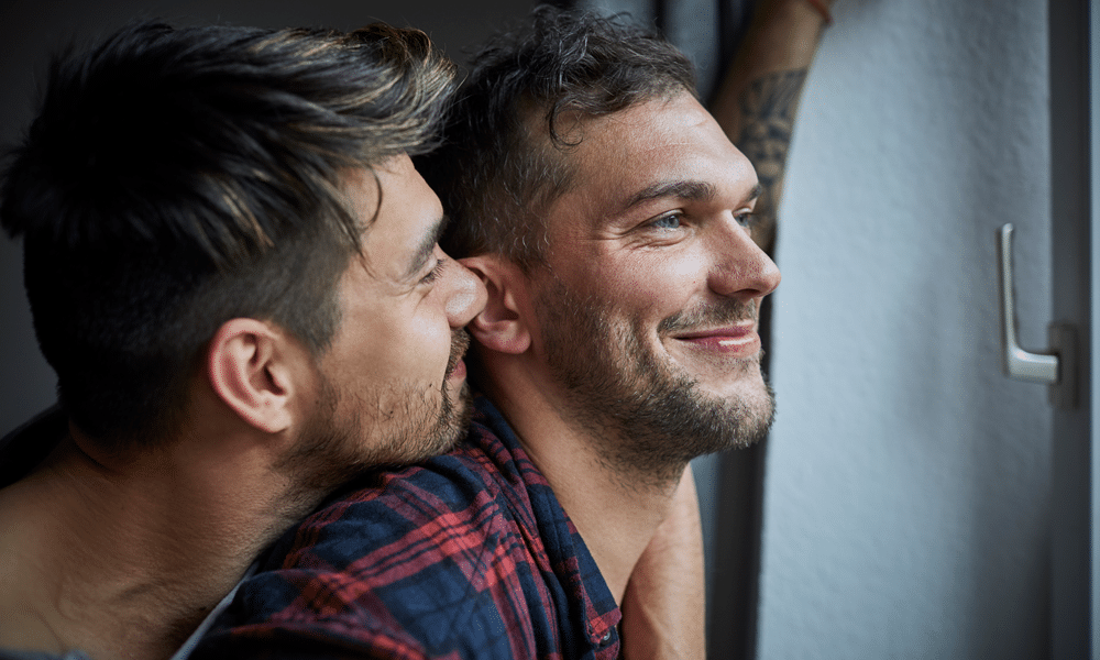 Gay man embracing boyfriend at the window