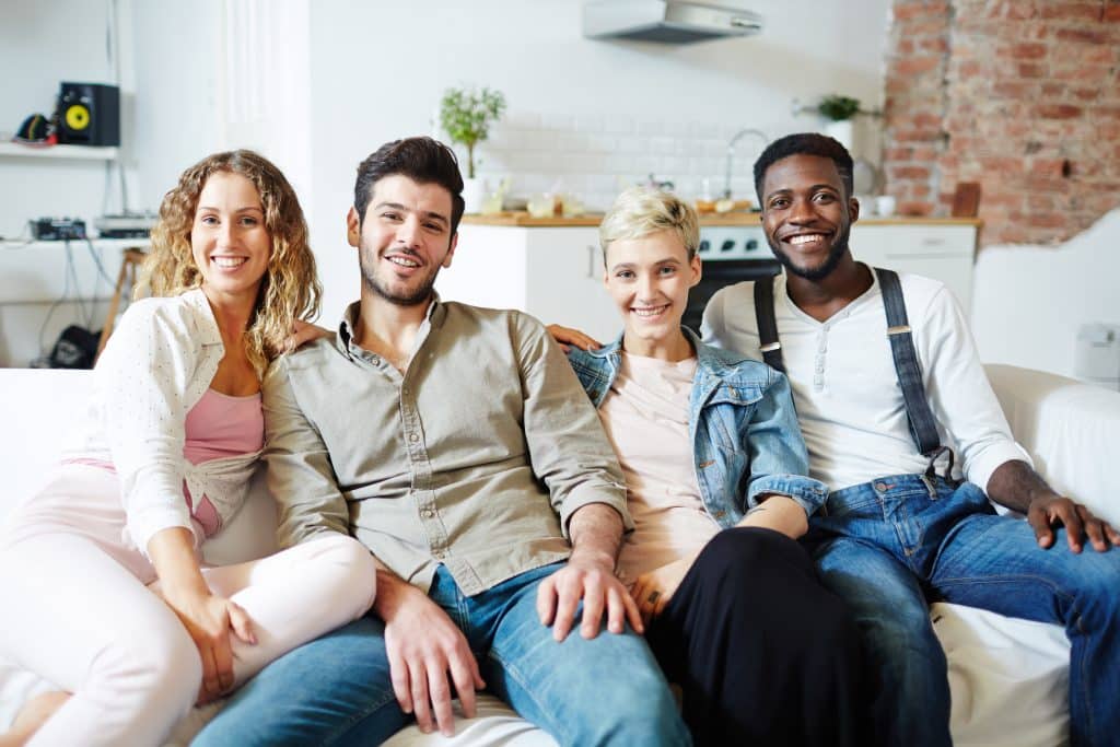 Young restful couples sitting on sofa while gathering after work or on weekend