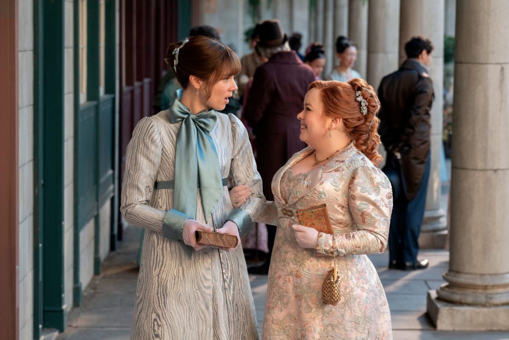 Penelope Bridgerton and Eloise Bridgerton laugh and walk together.