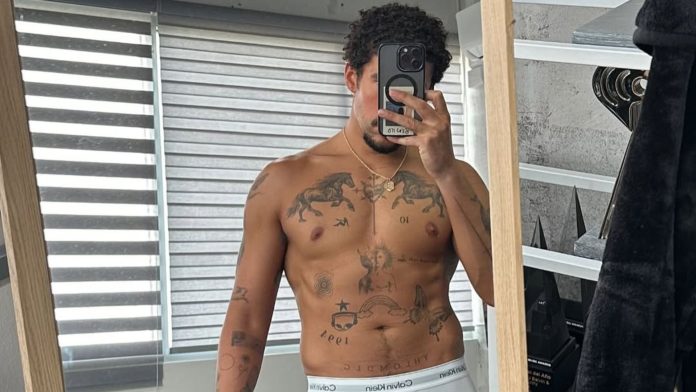 Bad Bunny takes a mirror selfie in white Calvin Klein briefs, displaying his muscular physique and tattoos.