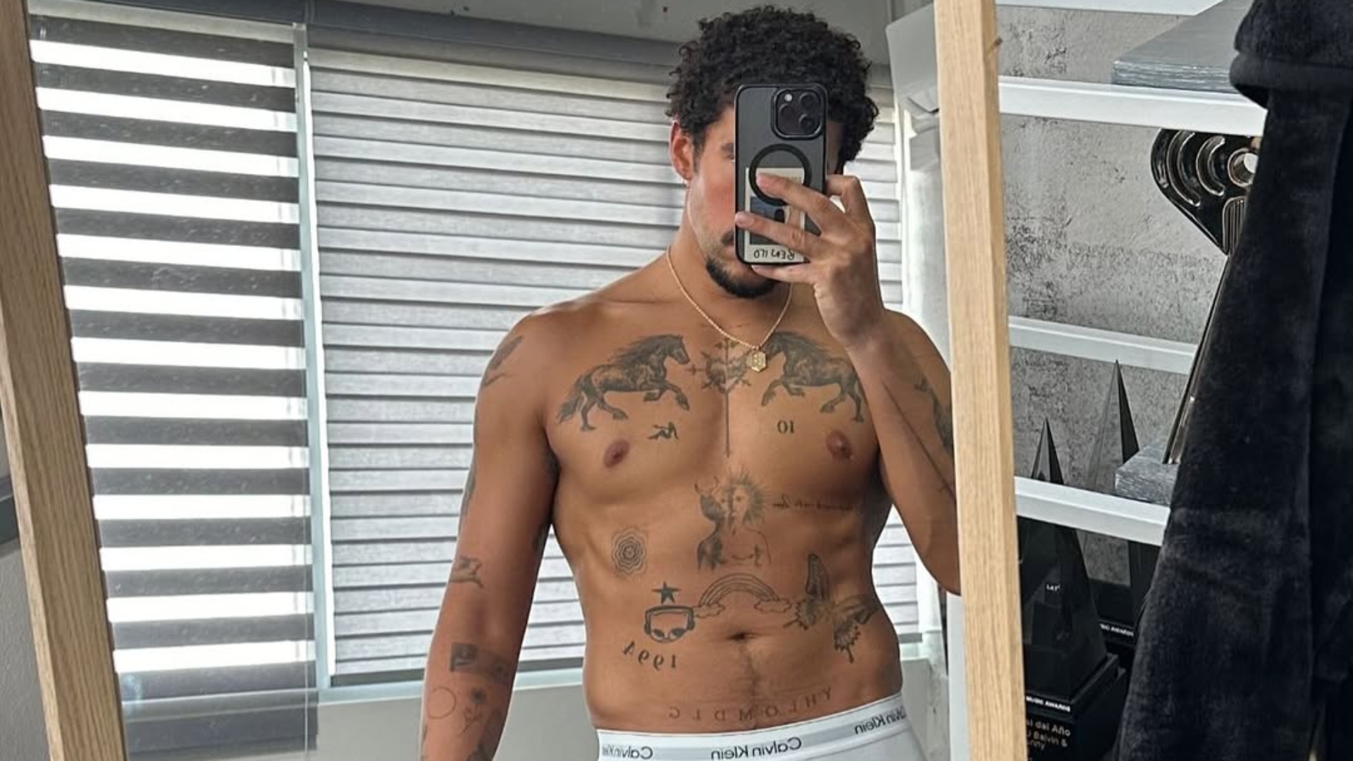 Bad Bunny takes a mirror selfie in white Calvin Klein briefs, displaying his muscular physique and tattoos.