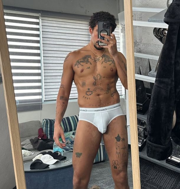 Bad Bunny takes a mirror selfie in white Calvin Klein briefs, displaying his muscular physique and tattoos.