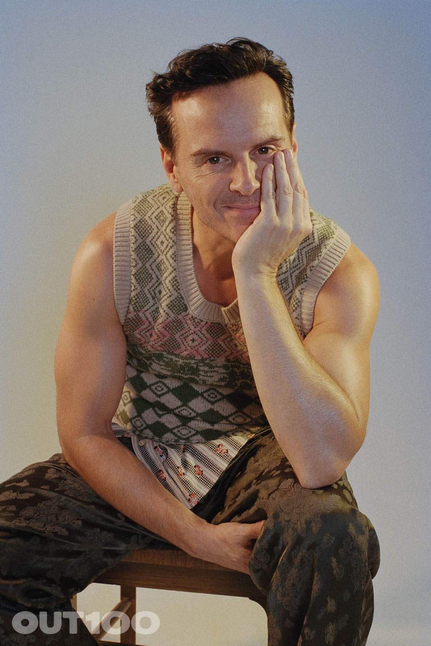 Andrew Scott sits on a stool in a patterned sleeveless top, resting his cheek on his hand, for OUT100.